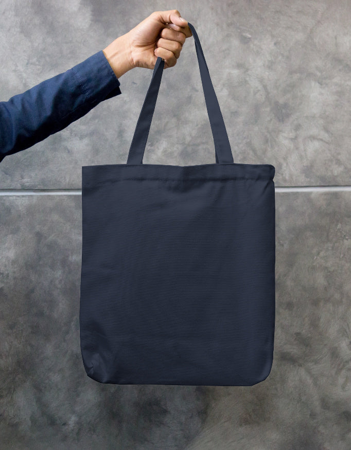 In an urban setting, a person in a beige shirt and cap carries the "Pink Petal Tote" by A Heartee Affair—an eco-friendly canvas bag with a vibrant pink and green floral design.