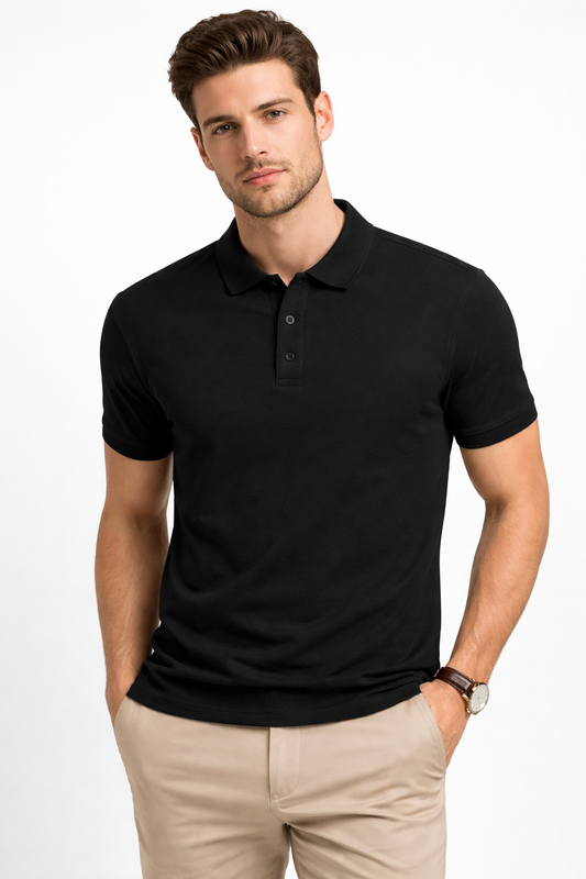 A man with short brown hair and a trimmed beard stands against a white background, hands in his pockets, wearing A Heartee Affair's Men's Plain Polo T-shirt in black with short sleeves and light beige pants, showcasing its regular fit.