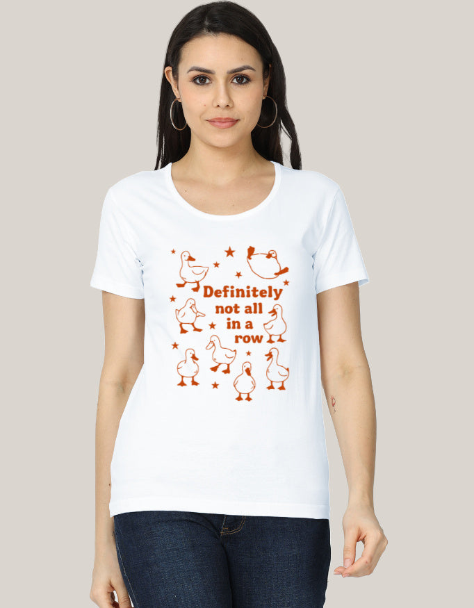 The Not In a Row Classic T-Shirt by A Heartee Affair is a white, 100% cotton tee featuring orange cartoon ducks and “Definitely not all in a row,” surrounded by stars, styled with denim shorts, sunglasses, jewelry, and coffee.